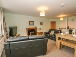 a living room with a leather couch and a tv at 2 Park Nook Close in Waberthwaite