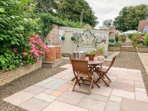 a patio with a table and chairs in a garden at Manor House in Warkworth