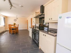 a kitchen with white cabinets and a black stove top oven at Glanyrafon Bungalow in Rhayader