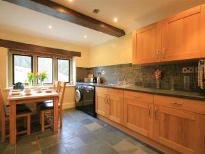 a kitchen with wooden cabinets and a table in it at Lakeside Cottage in Painswick