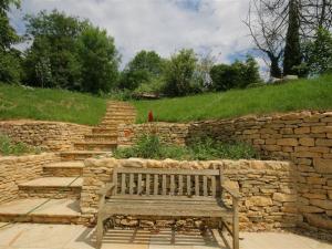 a wooden bench sitting in front of a stone wall at Upper Mill Barn in Quenington