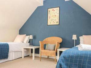 ein blaues Schlafzimmer mit 2 Betten und einem Stuhl in der Unterkunft Somerford Cottage in Malmesbury