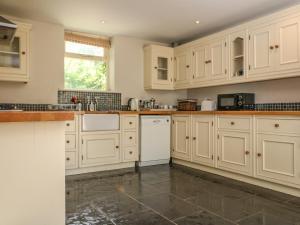 eine Küche mit weißen Schränken und Fliesenboden in der Unterkunft Somerford Cottage in Malmesbury