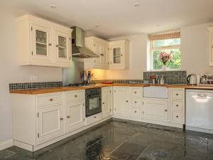 eine weiße Küche mit weißen Schränken und einem Fenster in der Unterkunft Somerford Cottage in Malmesbury