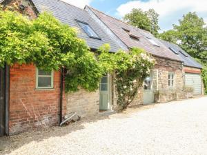 ein Backsteinhaus mit einer Einfahrt davor in der Unterkunft Somerford Cottage in Malmesbury