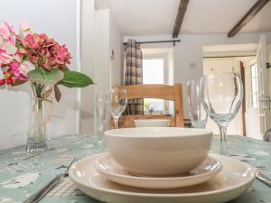 una mesa con un tazón y vasos y flores. en Appin Cottage, en Shipton under Wychwood