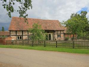 an old brick house with a wooden fence at Whites Farm Barn in Ledbury