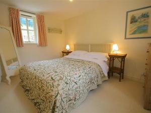 a bedroom with a large bed and two tables with lamps at Upper Mill Barn in Quenington