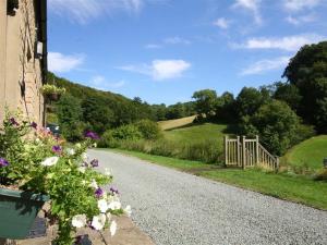 a gravel road with flowers on the side of a house at Lakeside Cottage in Painswick