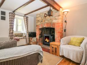 a living room with a stone fireplace and a couch at Appin Cottage in Shipton under Wychwood