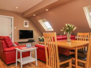 a living room with a table and a red couch at Temple Mews in Stow on the Wold