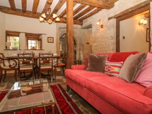een woonkamer met een rode bank en een tafel bij Bull Cottage in Burford