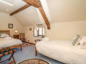 two beds in a attic bedroom with wooden beams at Bull Cottage in Burford