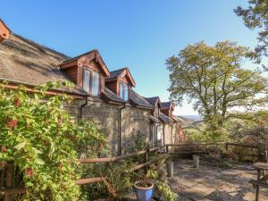 an old stone house with a wooden fence at Cedar Cottage in Llanidloes