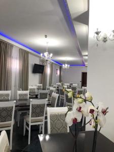 a dining room with white chairs and tables and flowers at Four S Palace in Băile Borşa