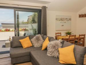 sala de estar con sofá gris y almohadas amarillas en Harbour View Retreat en Brixham