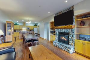 a living room with a fireplace and a dining room at Tree Tops in Big White