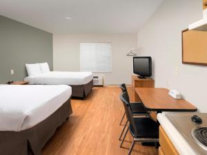 a hotel room with two beds and a desk and a kitchen at WoodSpring Suites Wilkes-Barre in Wilkes-Barre
