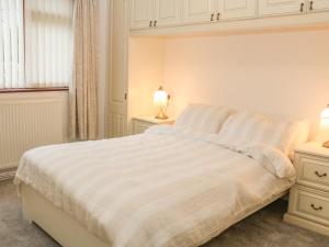 a bedroom with a white bed and a window at Eryl in Pwllheli