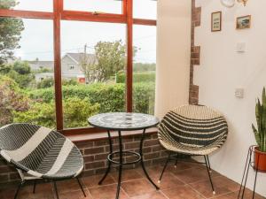 a patio with two chairs and a table and a window at Eryl in Pwllheli