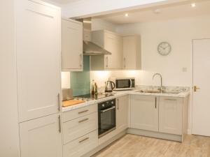 a kitchen with white cabinets and a clock on the wall at Eryl in Pwllheli +5 photos