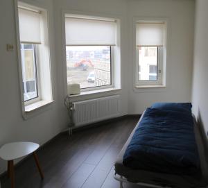 een slaapkamer met een bed en 2 ramen bij Beach Appartement in Vlissingen