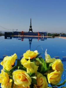 un jarrón lleno de rosas amarillas junto a un cuerpo de agua en Tahla Garden en Tahla