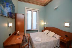 a bedroom with a bed and a desk and a window at Soana City Rooms in Genoa