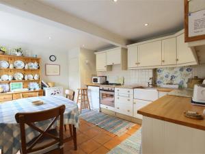 una cocina con armarios blancos y una mesa. en The Mews Cottage, en Tisbury