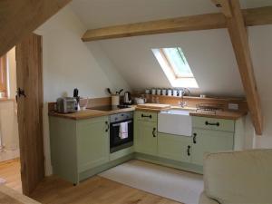 a small kitchen with green cabinets and a window at Avon Turn Barn, SALISBURY in Salisbury