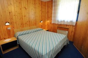 a bedroom with a bed and a desk and a window at Appartamenti CIMA LASTE in Mezzana