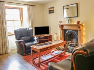 a living room with a fireplace and a television at Sea Breeze Cottage in Buckie