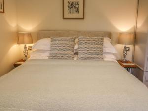 a bedroom with a large white bed with two lamps at The Bothy in Arncliffe