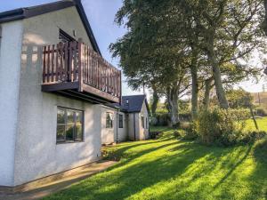 a house with a balcony on the side of a yard at Garth Cottage in Denbigh
