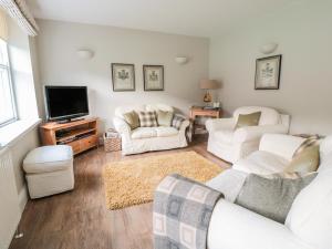 a living room with white furniture and a flat screen tv at Postmaster's Lodging in Cheltenham