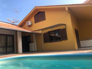 una casa con piscina frente a ella en Linda casa com piscina em Bombinhas, espaço inteiro, en Bombinhas