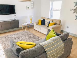 a living room with a gray couch and yellow pillows at Sandpipers in Anstruther