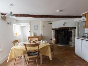 eine Küche und ein Esszimmer mit einem Tisch und einem Kamin in der Unterkunft Farrier's Lodge in Corfe Castle