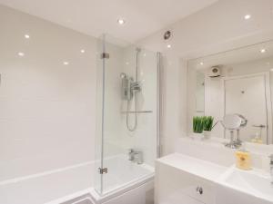 Un baño blanco con ducha y lavabo. en Cumbrae View, en Largs 15 fotos más