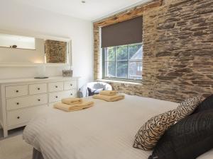 um quarto com uma cama branca e uma parede de pedra em 8 The Pottery em Dartmouth