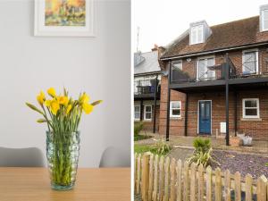 a vase of yellow flowers sitting on a table in front of a house at Swan Cottage in Arundel