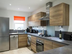 a kitchen with wooden cabinets and a sink and a dishwasher at Swan Cottage in Arundel