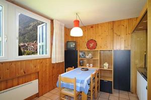 a dining room with a table and a kitchen with a window at Appartamenti CIMA LASTE in Mezzana