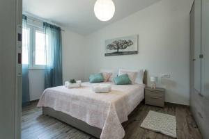 um quarto branco com uma cama grande com almofadas azuis e rosa em Lodge JoMi em Kaštel Novi