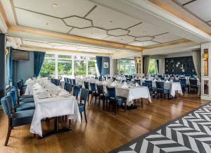 una sala da pranzo con tavoli e sedie bianchi di Sandymount Hotel a Dublino