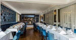 a dining room with white tables and blue chairs at Sandymount Hotel in Dublin