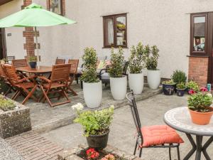 a patio with a table and chairs and potted plants at Bwlch Y Gwynt Bach in Llangefni