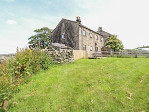 an old stone house on a hill with a grass field at 1 Horsehold Cottage in Hebden Bridge