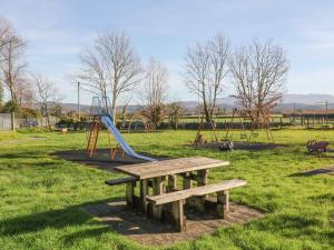 a park with a playground with a bench and a slide at 2 Bryn Eglwys in Porthmadog