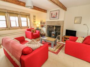a living room with red furniture and a fireplace at 1 Horsehold Cottage in Hebden Bridge